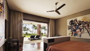 A modern hotel room with a large bed, a desk with a chair, a ceiling fan, and a view of palm trees and a pool.