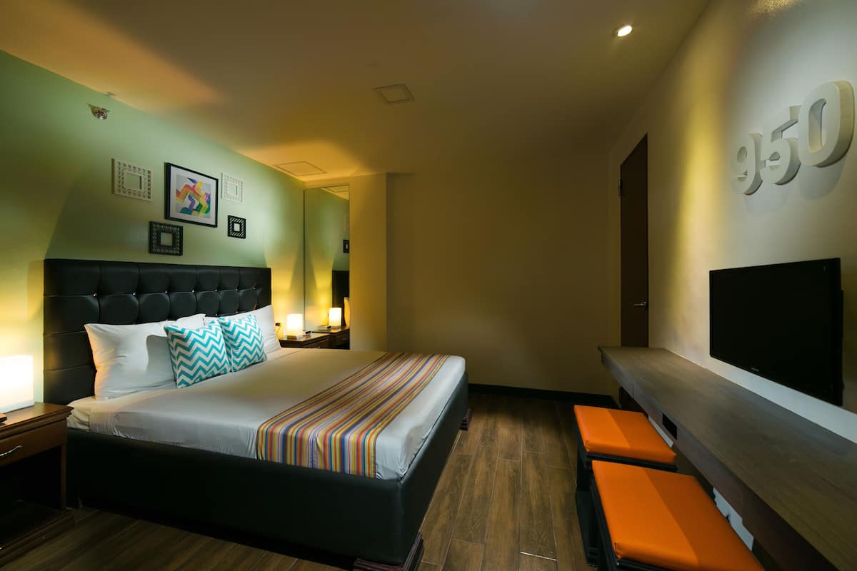 A hotel room with a large bed, a TV, and a seating area.