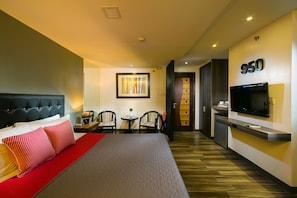 A hotel room with a bed, a TV, a desk with a chair, and a small table with a plant. - 950 Condotel (Angeles City)