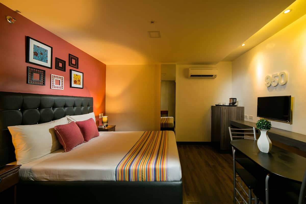 A hotel room with a large bed, a desk, and a TV.