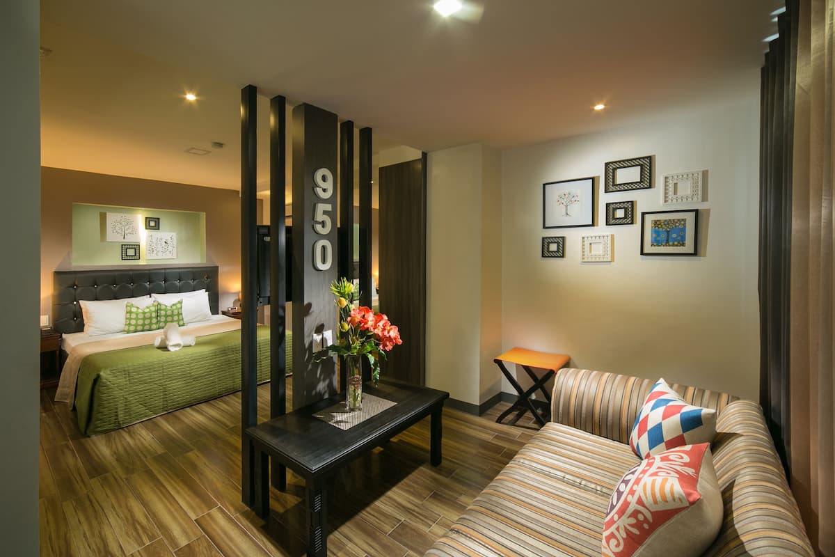 A hotel room with a bed, a sofa, a coffee table, and a wall with framed pictures.
