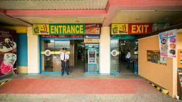 A supermarket entrance and exit with a Metrobank ATM, a sign for McDonald's, and a Dunkin' Donuts advertisement.