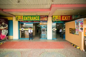 A supermarket entrance and exit with a Metrobank ATM, a sign for McDonald's, and a Dunkin' Donuts advertisement. - 950 Condotel (Angeles City)