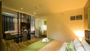A hotel room with a bed, a sofa, a TV, a desk, and a kitchenette. - 950 Condotel (Angeles City)