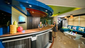A hotel reception area with a curved counter, a blue and green ceiling, and a modern interior design. - 950 Condotel (Angeles City)