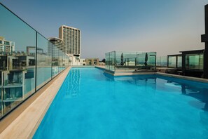 A rooftop pool with glass railings, a high-rise building in the background, and a clear sky. - Spinola Hotel (St. Julian's)