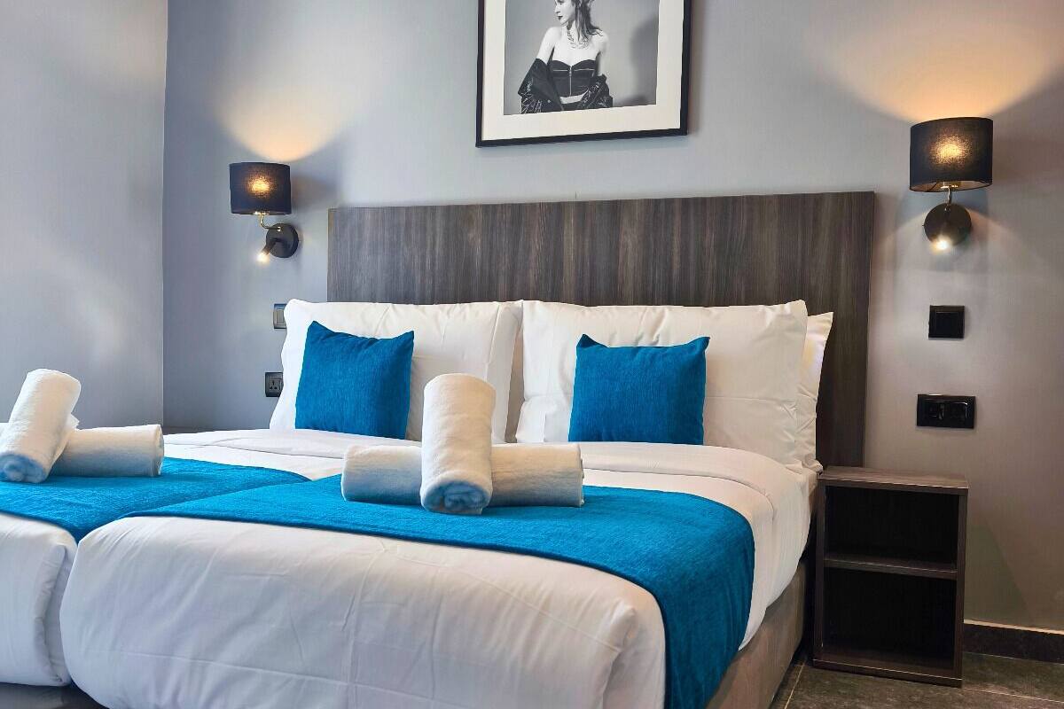 A modern hotel room with a large bed, two bedside tables, and a framed picture on the wall.