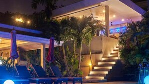 Un área de piscina moderna con sillones de descanso y una escalera que sube a un nivel superior.