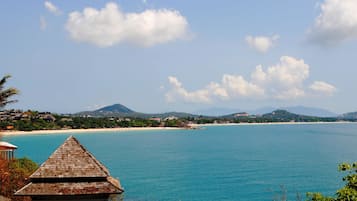 A coastal view with a beach, clear sky, and distant mountains.