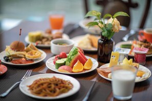 Ein Frühstücksbuffet mit verschiedenen Speisen, eine Vase mit Blumen und ein Glas Orangensaft.