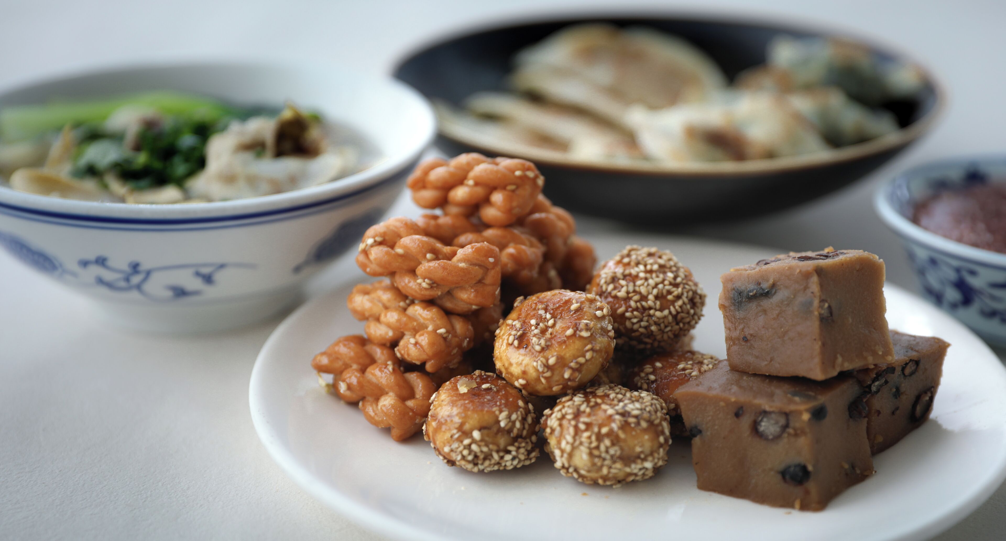 A plate with various food items, including sweets and a bowl of soup.