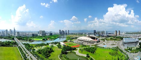 A panoramic view of a cityscape with a stadium, green spaces, and a river.