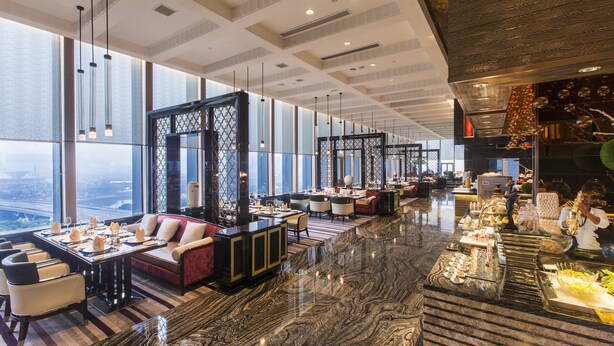 A spacious hotel lobby with a marble floor, seating areas, and a buffet.