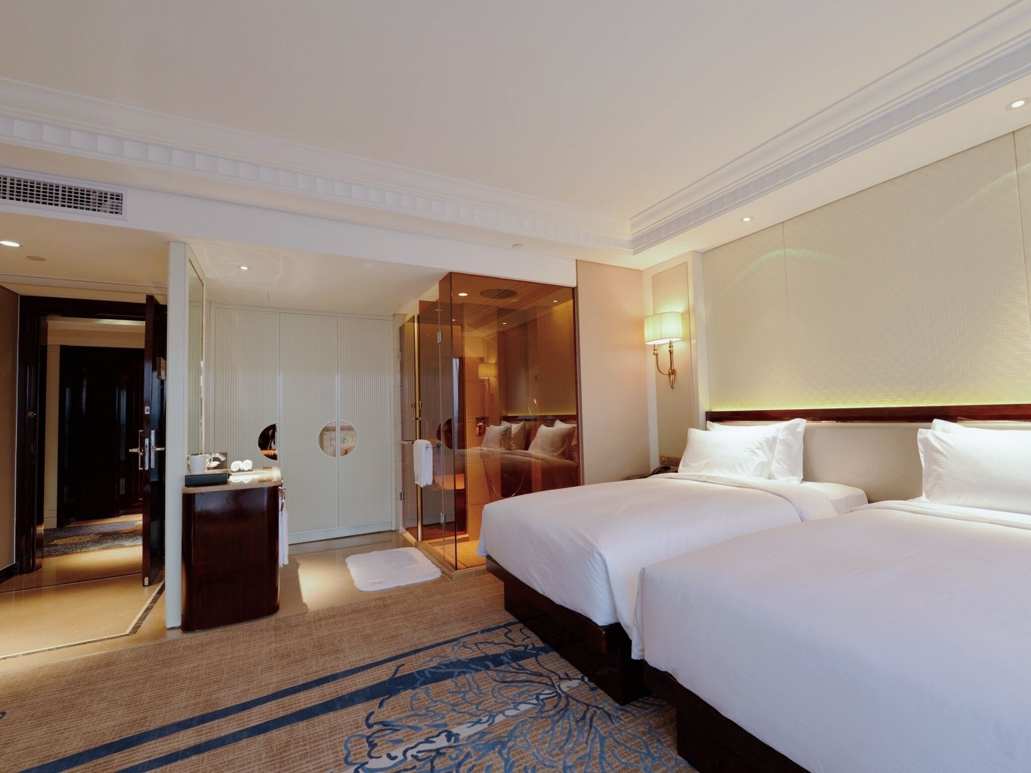 Habitación de hotel con dos camas, un espejo, tocador y vestidor.