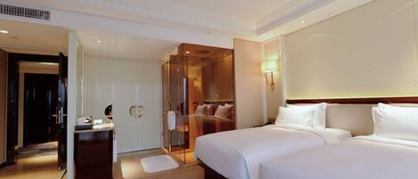 Habitación de hotel con dos camas, un espejo, tocador y vestidor.