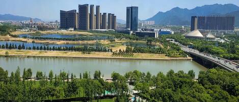 A cityscape with modern high-rise buildings, a bridge, and a lake surrounded by greenery.