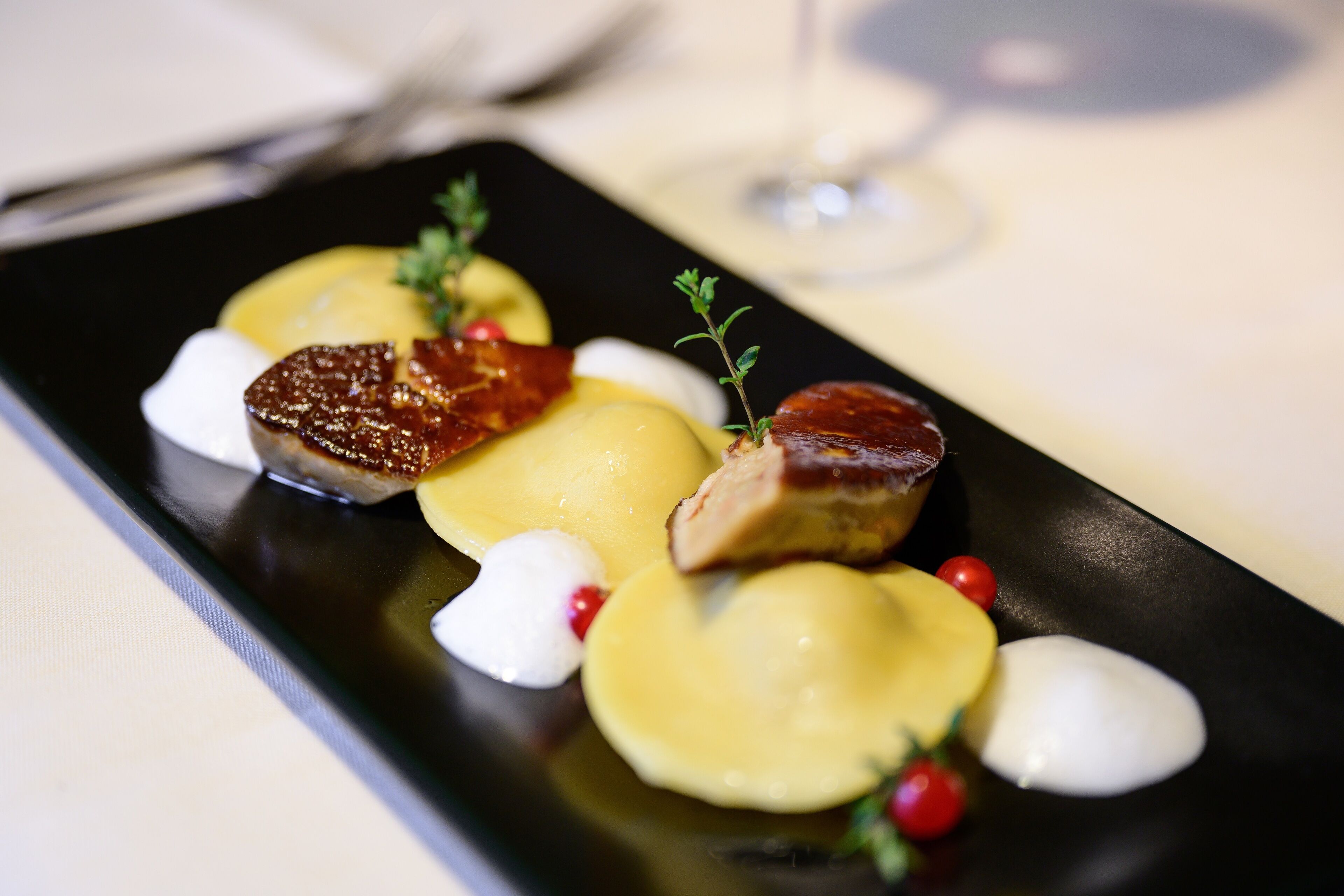 Un plato rectangular negro con comida, incluyendo carne, patatas y guarniciones.