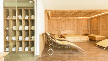 A wooden-paneled room with a glass shower enclosure, a bed with a headboard, and a bench.