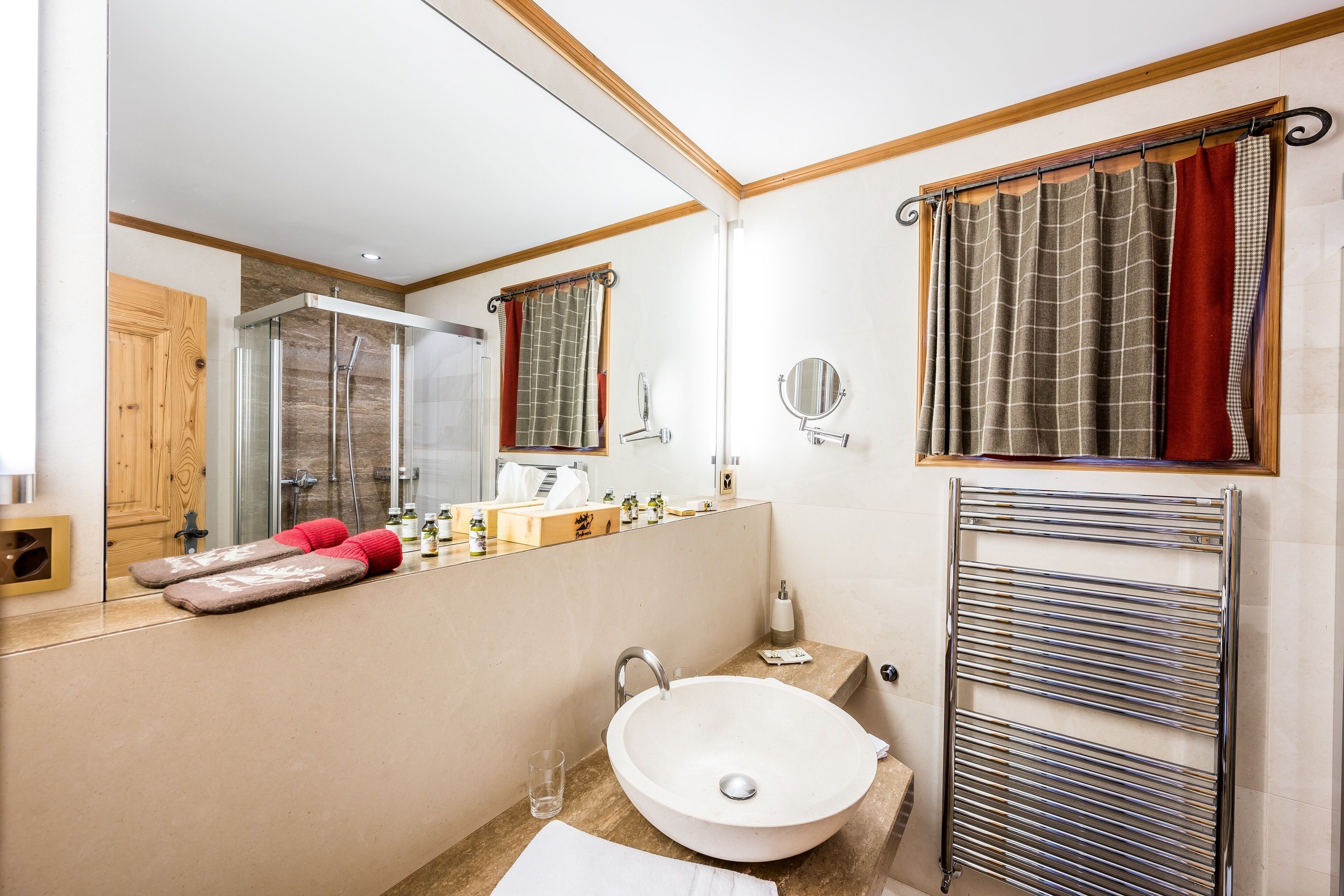 A modern bathroom with a large mirror, a white sink, a glass shower enclosure, and a towel rack.
