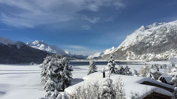 Een besneeuwd berglandschap met een meer en een chalet.
