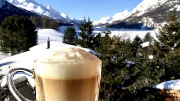 Een transparante kop koffie op een schotel, met een besneeuwd berglandschap op de achtergrond.