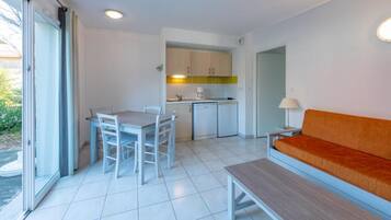 A compact living space with a dining area, kitchenette, and a sofa.