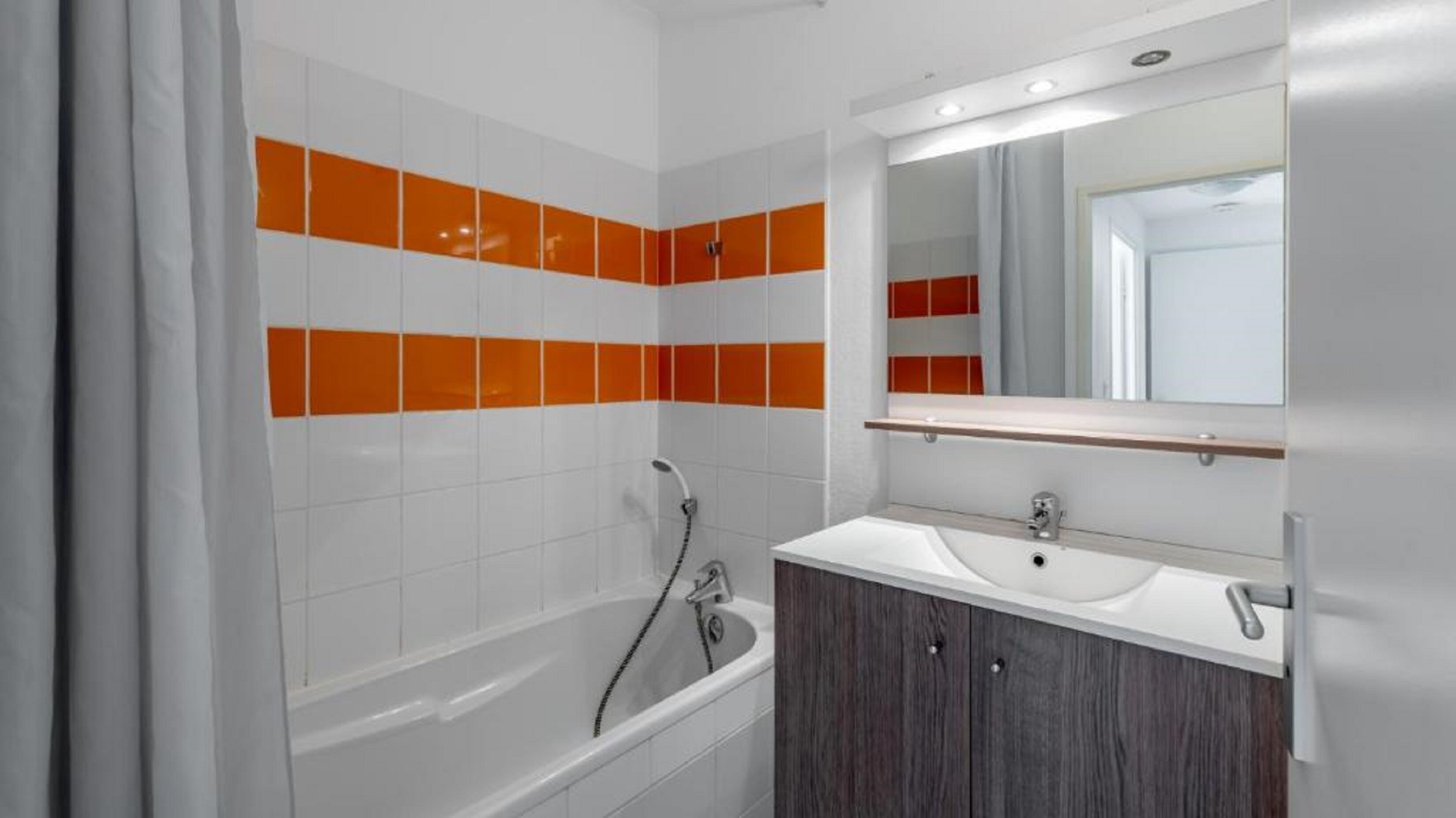 Un bany modern amb banyera, un lavabo i un mirall.