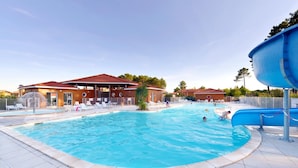 A swimming pool with lounge chairs and a water slide.