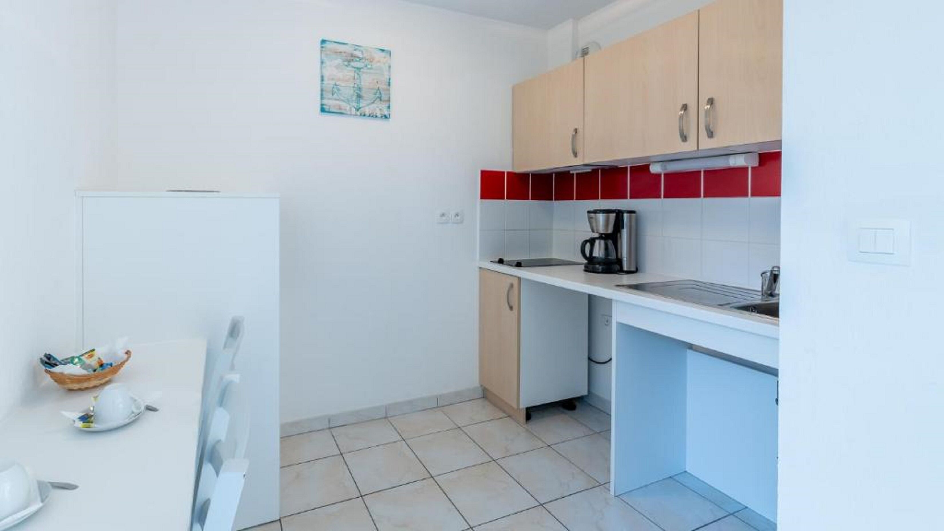 A compact kitchen with a white refrigerator, a coffee maker, and a sink.