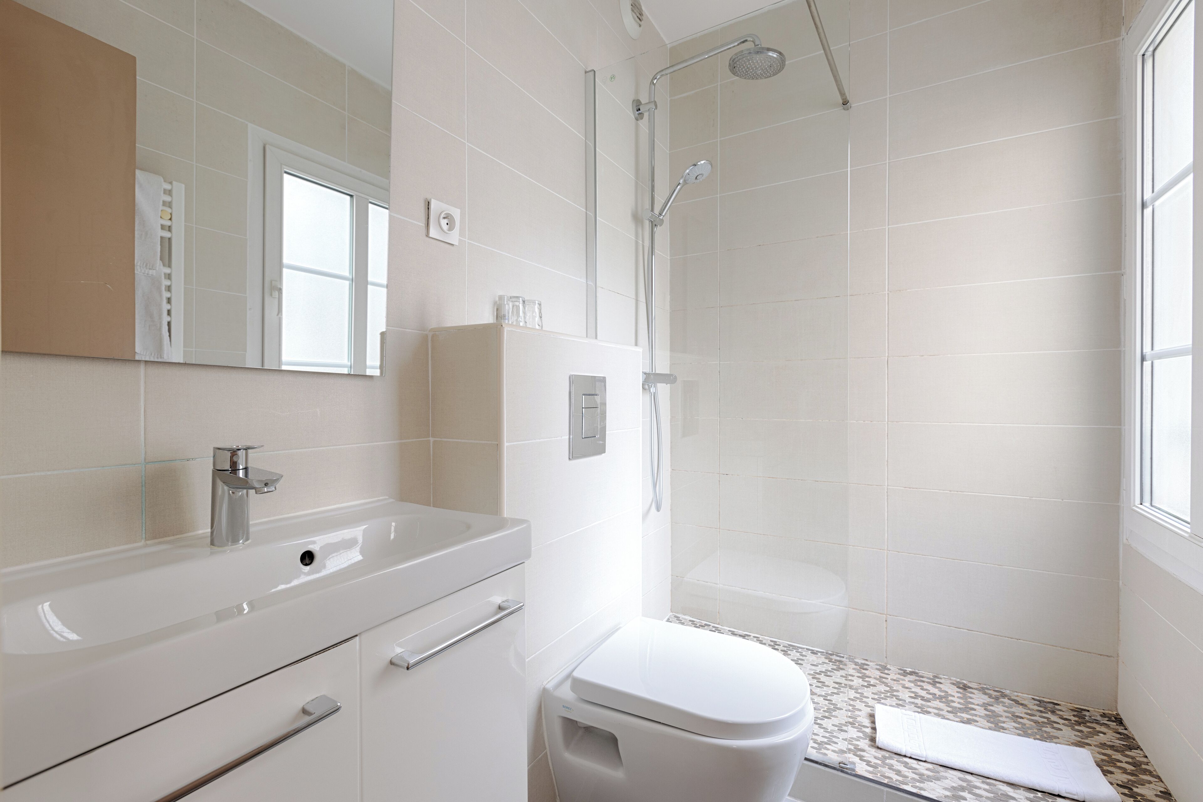 A modern bathroom with a white sink, mirror, and toilet.