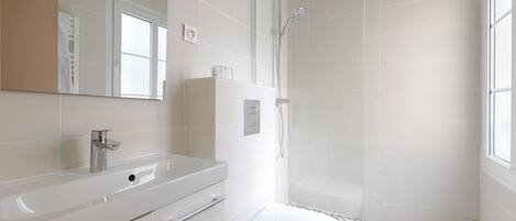 A modern bathroom with a white sink, mirror, and toilet.