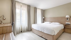 Een hotelkamer met een groot bed, een bureau en een stoel.