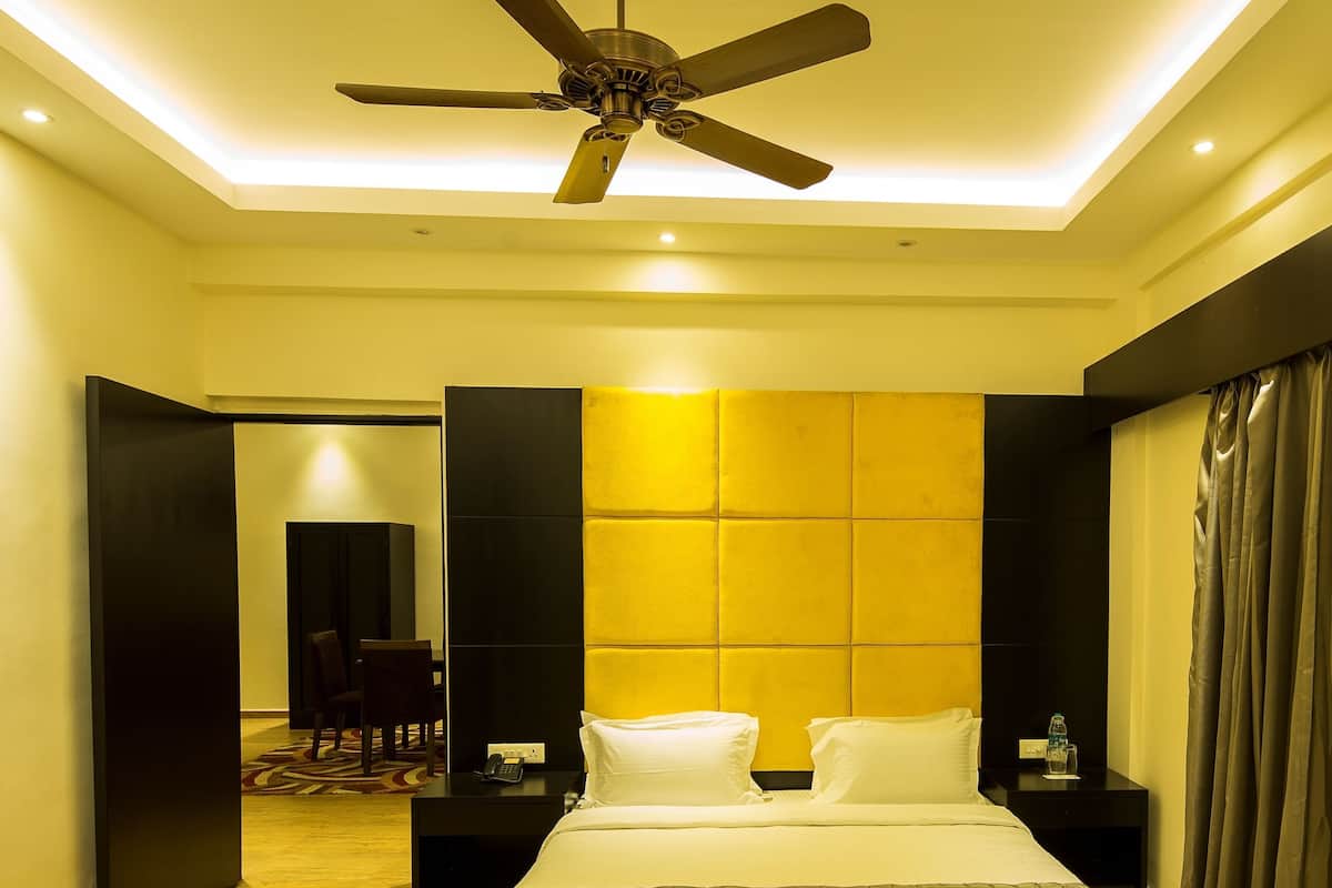 Une chambre d’hôtel équipée d’un lit, de tables de chevet, d’un ventilateur de plafond et présentant un design moderne.