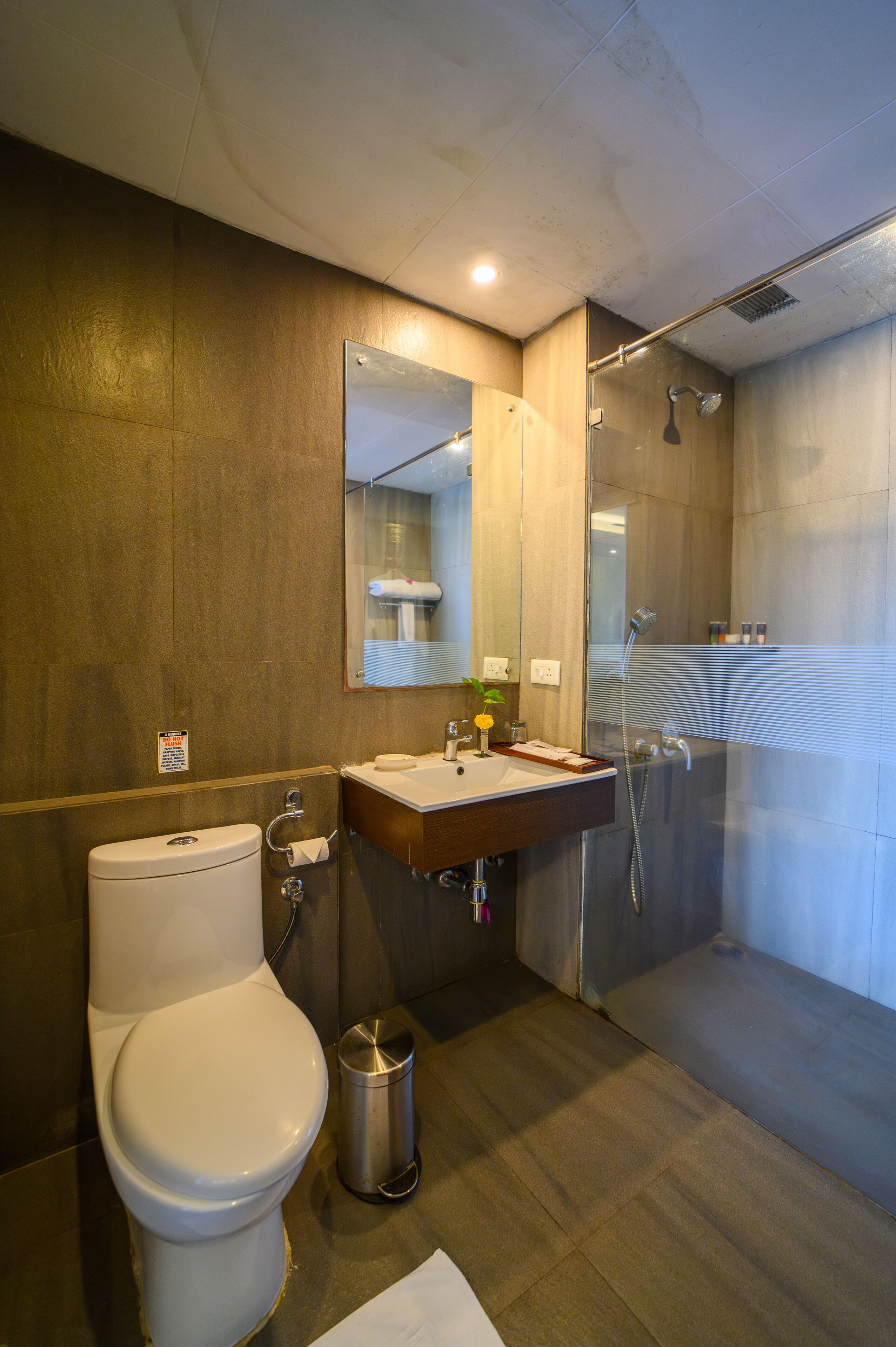 A modern bathroom with a toilet, sink, mirror, and shower.