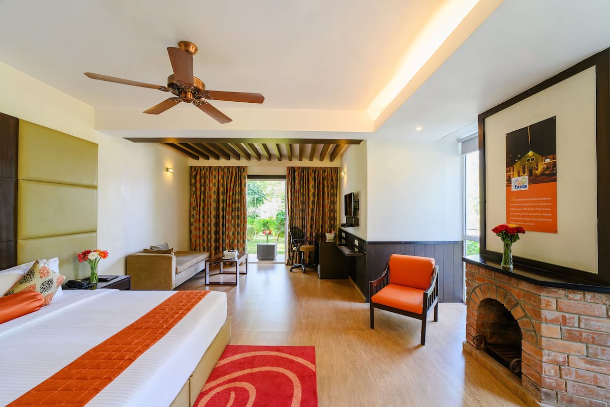 Une chambre d’hôtel équipée d’un lit, d’un bureau, d’une chaise, d’une cheminée et d’un ventilateur de plafond.