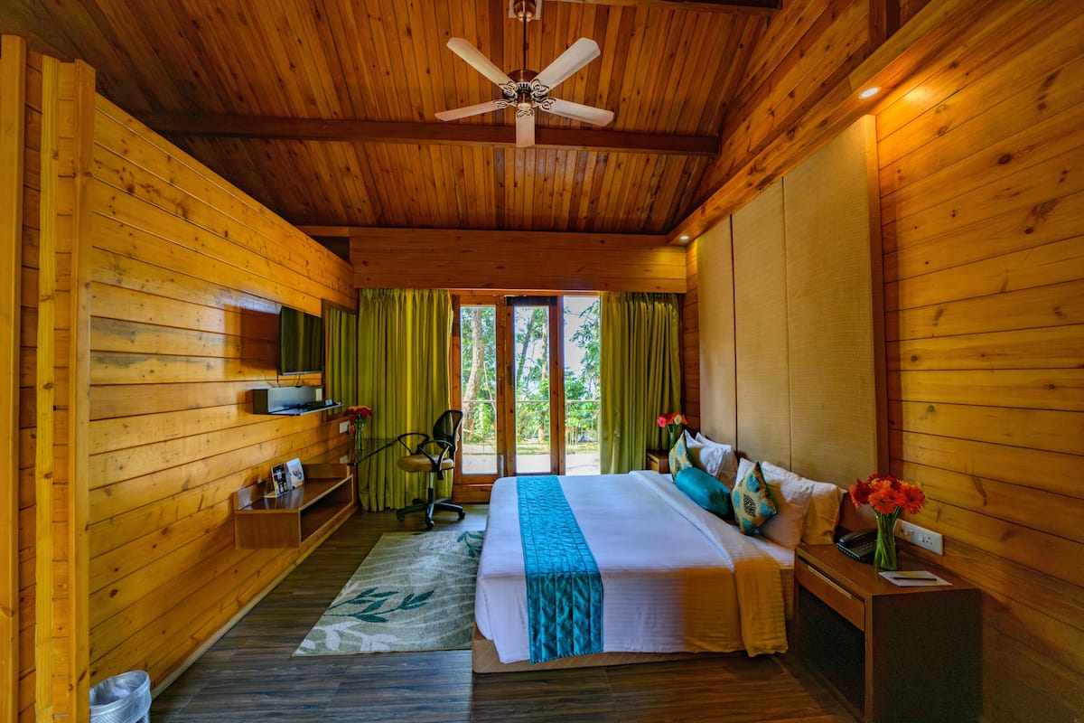 Une pièce de style cabane en bois, comprenant un lit, un bureau, une chaise et un ventilateur de plafond.