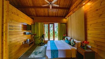 Una habitación de cabaña de madera con cama, escritorio, silla y ventilador de techo.