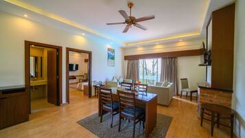 A modern living room with a dining area, a ceiling fan, and a large window with curtains.
