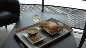 A tray with a sandwich, a bowl of soup, and a glass of white wine on a table.