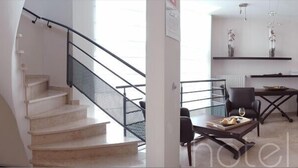 A modern hotel room with a staircase, a dining area with a table and chairs, and a view of the outside.