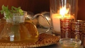A candle, a glass pitcher, and a small bowl on a table.