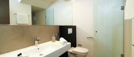 Un baño moderno con un lavamanos grande, espejo y retrete.