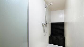 A modern bathroom with white and black tiles, a shower with a handheld showerhead, and a white bathtub.