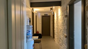 A narrow hallway with a water dispenser, a chair, and a door. - La Porta Luxury Rooms (Split)