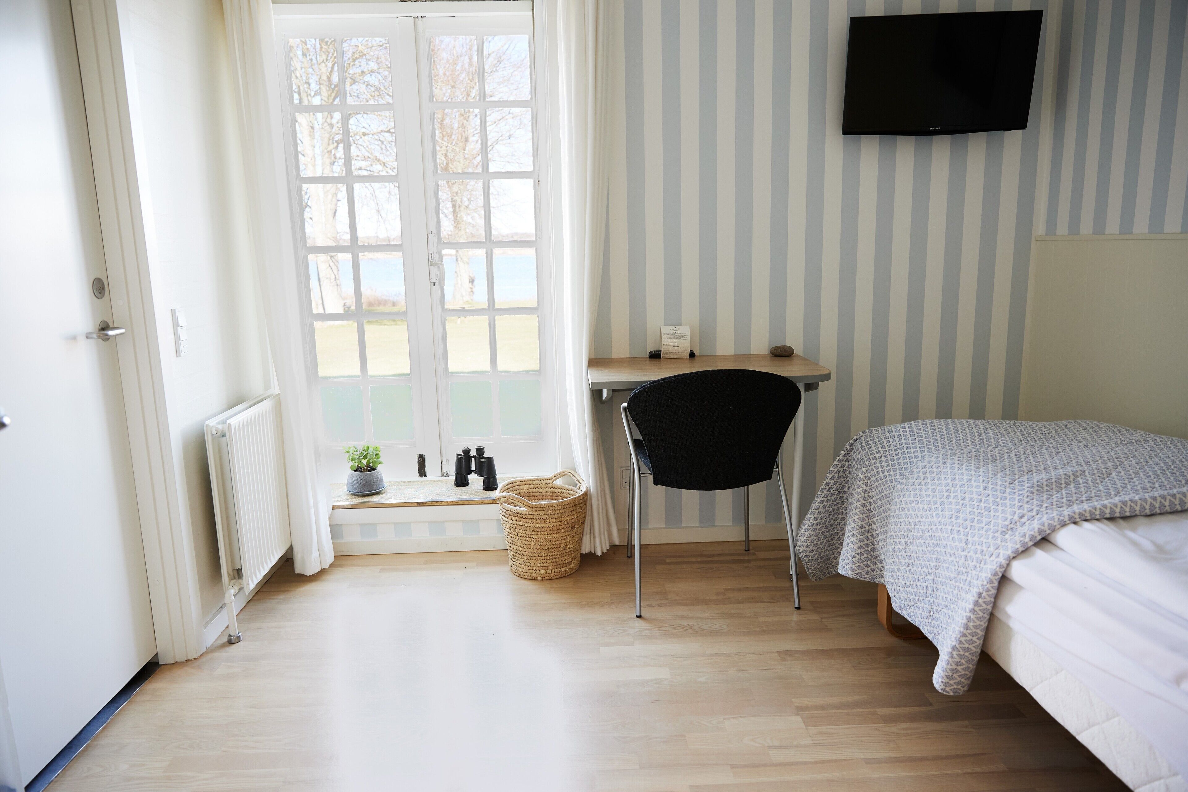 Un dormitorio con cama, escritorio, silla, ventana y televisor.