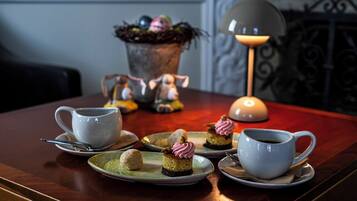 A table with a teapot, cups, and pastries.