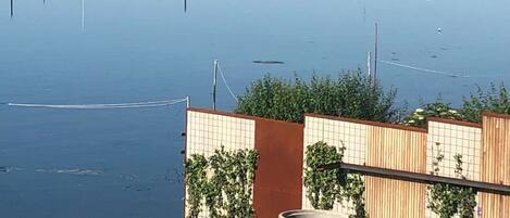 Un lago tranquilo con barcos, una valla de madera y una zona cubierta de césped.