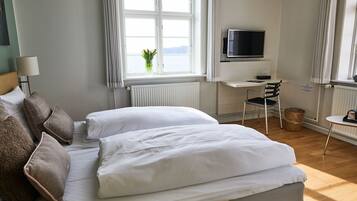 Une chambre d’hôtel bien aménagée, avec un grand lit, un bureau équipé d’un ordinateur, une télévision et une vue sur la mer par la fenêtre.