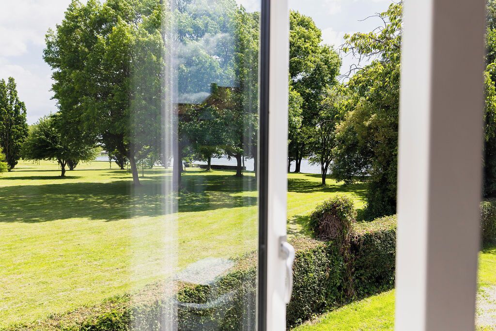 A view through a window of a park with trees and a grassy area.