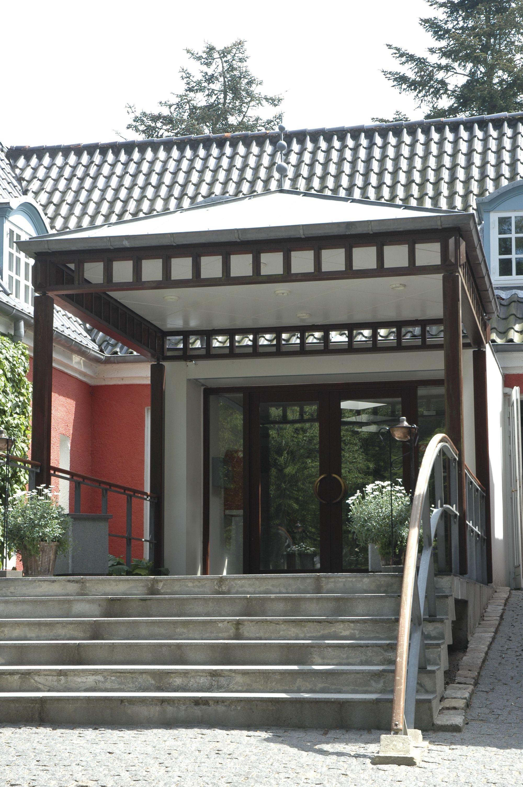 A building with a tiled roof, a covered entrance, and a staircase leading up to the entrance.